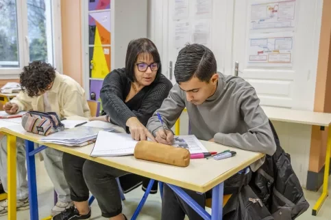 Jeune collégien en train de travailler en classe accompagné de son AESH