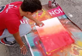 Jeune en train de faire de la peinture à la bombe sur une toile
