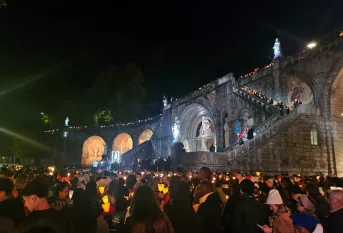 pelerins avec des torches illuminsées devant un monument embléùatique de Lourdes
