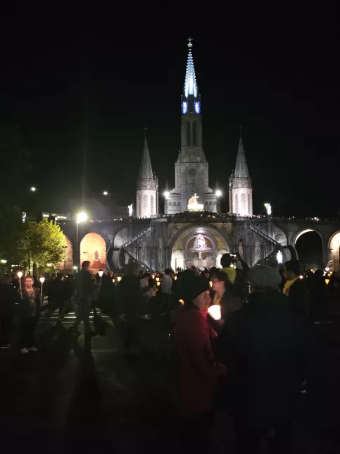 Basilique Notre Dame du Rosaire illuminée à Lourdes avec des pèlerins. 