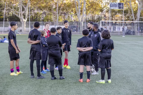 Groupe de jeunes en train d'écouter l'entraineur pendant la séance d'entraînement de la section foot