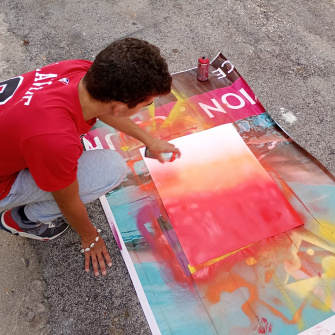 Jeune en train de faire de la peinture à la bombe sur une toile