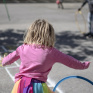 Petite fille de maternelle qui joue avec un cerceau dans la cours de récréation