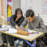 Jeune collégien en train de travailler en classe accompagné de son AESH